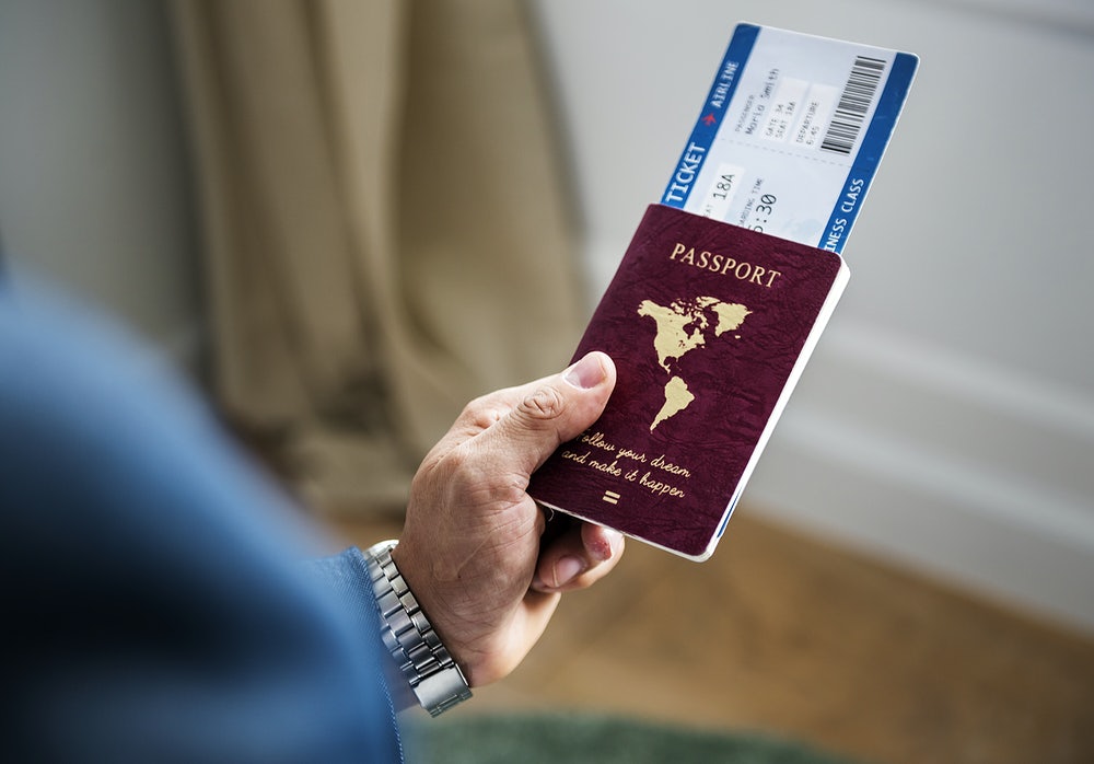 Person holding passport and plane ticket